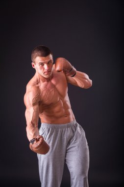 Kaslı adam boks eldiven koyu arka plan üzerinde. Profesyonel boksör boks kas raflar içinde gösterir. Güzel kas vücut boksör. Fotoğraflar spor dergileri, afiş ve Web siteleri için.