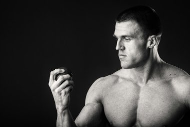 Vücut geliştirmeci bir meyve karanlık bir arka plan üzerinde tutarak. Gösteri profesyonel atlet sağlıklı beslenme.