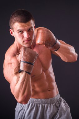 Kaslı adam boks eldiven koyu arka plan üzerinde. Profesyonel boksör boks kas raflar içinde gösterir. Güzel kas vücut boksör. Fotoğraflar spor dergileri, afiş ve Web siteleri için.
