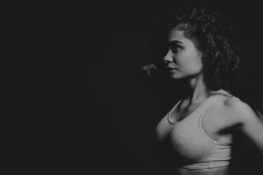 Profesyonel sporcu karanlık bir arka plan üzerinde damgalı fitness ile poz. Güzel spor kız onun elleri ve kasları geri gösterir. Konsantreleri vücuduna üzerinde çalış. Dergi spor için fotoğraflar.