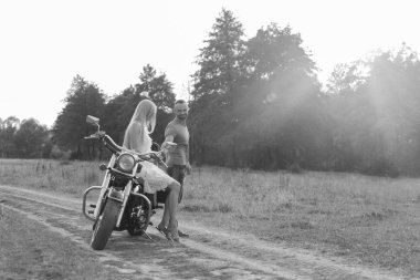 Siyah ve beyaz fotoğraf motorcu çift bir motosiklet alanında.