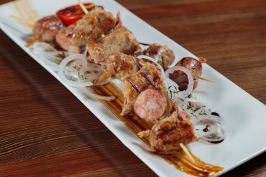 Beyaz bir tabakta sebze ve sos ile lezzetli sosis.