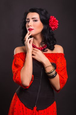 Karanlık bir arka plan üzerinde kırmızı ve siyah elbiseli güzel bir genç kadın portresi.