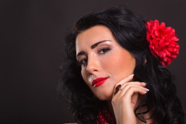 Karanlık bir arka plan üzerinde kırmızı ve siyah elbiseli güzel bir genç kadın portresi.