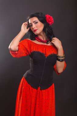 Karanlık bir arka plan üzerinde kırmızı ve siyah elbiseli güzel bir genç kadın portresi.
