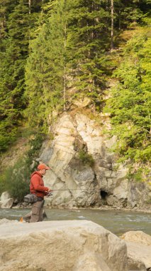 Balıkçı bir dağ nehir üzerinde egzotik balık yakalamak. Alabalık balıkçılık Karpat nehirler. Dağları nın el değmemiş doğası. Balıkçılık ve doğal dergiler, posterler ve Web siteleri için fotoğraf.