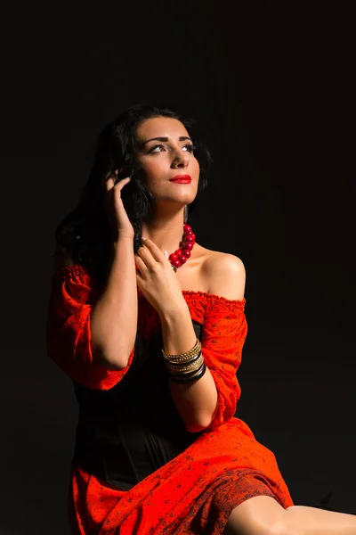 Retrato de una hermosa joven vestida de rojo y negro sobre un fondo oscuro . — Foto de Stock