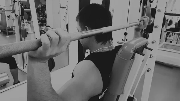 En man utför en övning med en skivstång. Ung tyngdlyftare i gymmet. Atletisk, friska, muskulös kille. Hälsosam livsstilskoncept. Tyngdlyftning. — Stockfoto