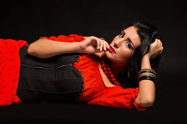 Retrato de uma bela jovem mulher em vestido vermelho e preto em um fundo escuro . — Fotografia de Stock