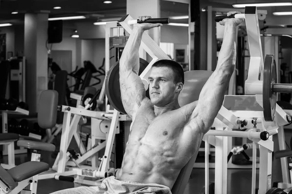 Homme musclé fort faisant des exercices dans la salle de gym. Beau corps sur une photo en noir et blanc. Mode de vie sain . — Photo