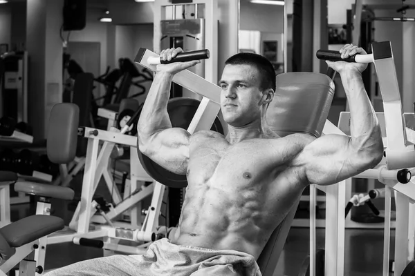 Сильный мускулистый человек делает упражнения в спортзале. Красивое тело на черно-белом фото. Здоровый образ жизни . — стоковое фото