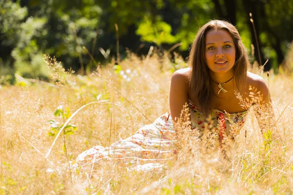 A young and attractive girl in beautiful summer dress middle of sunny meadows. Cheerful girl basking in the warm rays of the summer sun. Beautiful image of a carefree girl. Photos for magazines, — Stock Photo, Image