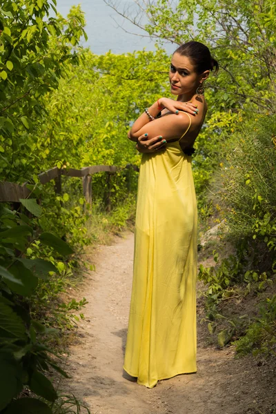 Retrato de la niña sobre el telón de fondo de un hermoso paisaje natural. Chica en la naturaleza en un hermoso vestido amarillo . — Foto de Stock