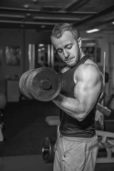 Man at the gym. Man makes exercises dumbbells. Sport, power, dumbbells, tension, exercise - the concept of a healthy lifestyle. Article about fitness and sports. — Stock Photo, Image