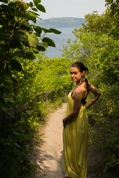 美しい自然の風景を背景に少女の肖像画。自然の中で美しい黄色のドレスの女の子. — ストック写真