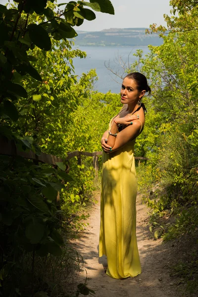 Portret van het meisje tegen de achtergrond van een prachtig natuurlandschap. Meisje in de natuur in een mooie gele jurk. — Stockfoto