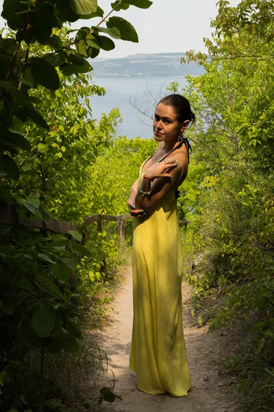 Porträt des Mädchens vor dem Hintergrund einer wunderschönen Naturlandschaft. Mädchen in der Natur in einem schönen gelben Kleid. — Stockfoto