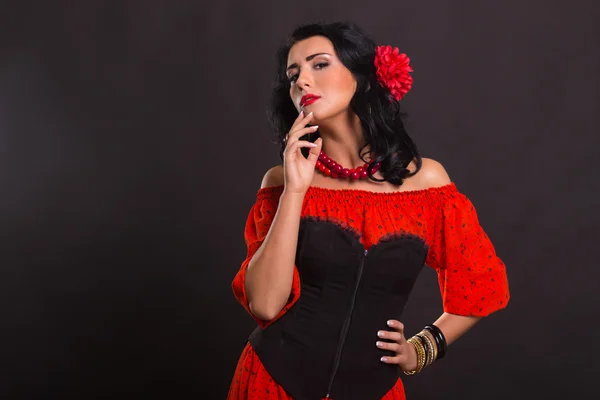 Karanlık bir arka plan üzerinde kırmızı ve siyah elbiseli güzel bir genç kadın portresi. — Stok fotoğraf