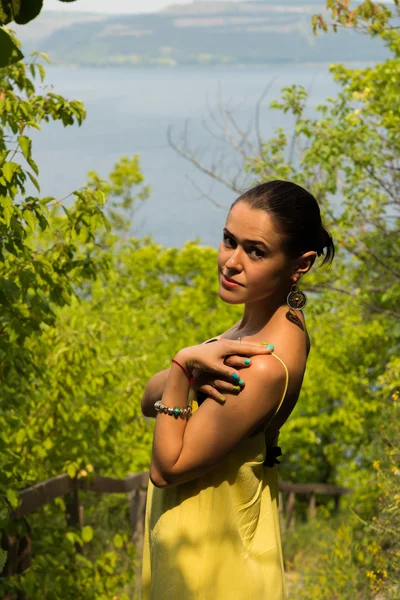 Retrato da menina contra o pano de fundo de uma bela paisagem natural. Menina na natureza em um belo vestido amarelo . — Fotografia de Stock