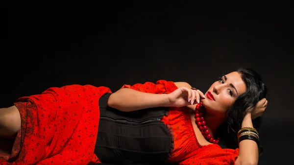 Retrato de una hermosa joven vestida de rojo y negro sobre un fondo oscuro . —  Fotos de Stock