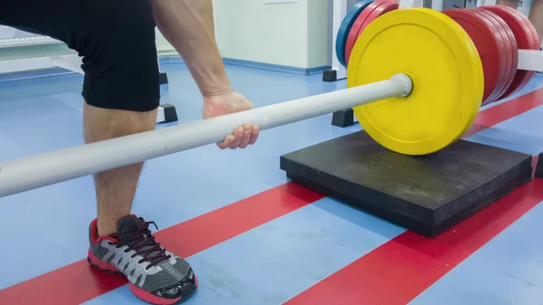 En man utför en övning med en skivstång. Ung tyngdlyftare i gymmet. Atletisk, friska, muskulös kille. Hälsosam livsstilskoncept. Tyngdlyftning. — Stockfoto