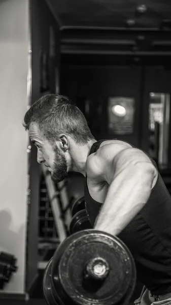 Hombre en el gimnasio. El hombre hace ejercicios de pesas. El deporte, el poder, las pesas, la tensión, el ejercicio - el concepto de un estilo de vida saludable. Artículo sobre fitness y deportes . — Foto de Stock