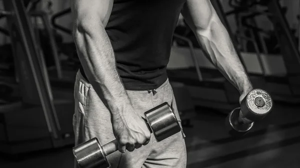 Um homem no ginásio. O homem faz exercícios halteres. Esporte, poder, halteres, tensão, exercício - o conceito de um estilo de vida são. Artigo sobre fitness e esportes . — Fotografia de Stock