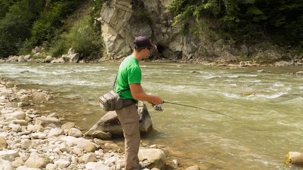 Pesca. Pesca en las tierras altas. Pescador en la orilla de una montaña, río rápido. Pesca de truchas en el río. Vacaciones activas en las montañas . — Foto de Stock