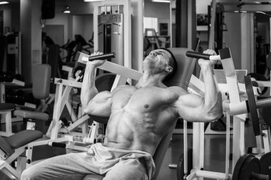 Kaslı adam spor salonunda ağırlık ile çalışma dışarı. Adam egzersizleri yapar.