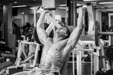 Kaslı adam spor salonunda ağırlık ile çalışma dışarı. Adam egzersizleri yapar.