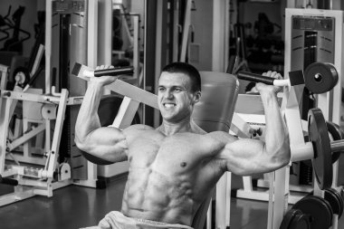 Kaslı adam spor salonunda ağırlık ile çalışma dışarı. Adam egzersizleri yapar.