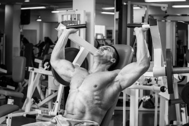 Kaslı adam spor salonunda ağırlık ile çalışma dışarı. Adam egzersizleri yapar.