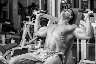 Kaslı adam spor salonunda ağırlık ile çalışma dışarı. Adam egzersizleri yapar.