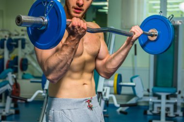 Kaslı adam spor salonunda ağırlık ile çalışma dışarı. Adam egzersizleri yapar.