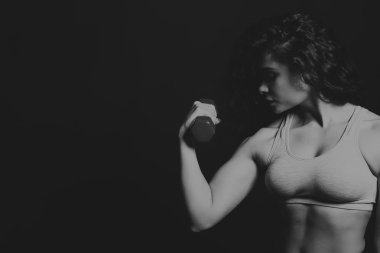 Güzel atlet karanlık bir arka plan üzerinde siyah ve beyaz fotoğraf. Kadın fitness. Dumbell ile çalışma. Fotoğraflar spor dergileri, afiş ve Web siteleri için.