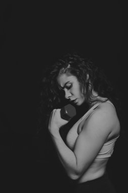 Güzel atlet karanlık bir arka plan üzerinde siyah ve beyaz fotoğraf. Kadın fitness. Dumbell ile çalışma. Fotoğraflar spor dergileri, afiş ve Web siteleri için.