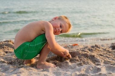 Sahilde erkek şort. Deniz kum ile oynayan çocuk. Sevinç ve eğlenceli çocuklar için. Güzel sıcak bir gün. Çocuk dergi ve Web siteleri için fotoğraf.