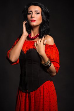 Kırmızı bir elbise şık ve seksi kadın. Güzel esmer kırmızı stüdyoda portresi. Duygusal portre.