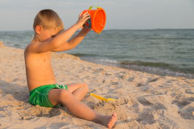Sahilde erkek şort. Deniz kum ile oynayan çocuk. Sevinç ve eğlenceli çocuklar için. Güzel sıcak bir gün. Çocuk dergi ve Web siteleri için fotoğraf.