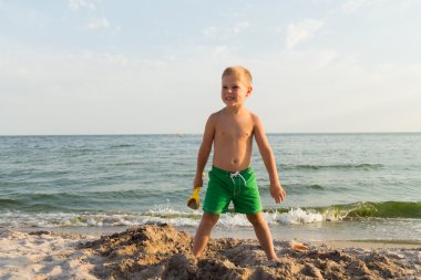 Sahilde erkek şort. Deniz kum ile oynayan çocuk. Sevinç ve eğlenceli çocuklar için. Güzel sıcak bir gün. Çocuk dergi ve Web siteleri için fotoğraf.