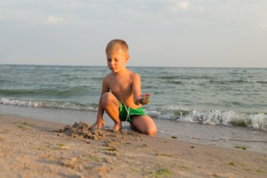 Sahilde erkek şort. Deniz kum ile oynayan çocuk. Sevinç ve eğlenceli çocuklar için. Güzel sıcak bir gün. Çocuk dergi ve Web siteleri için fotoğraf.