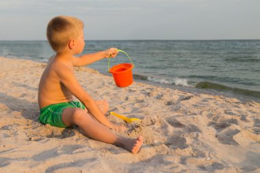Sahilde erkek şort. Deniz kum ile oynayan çocuk. Sevinç ve eğlenceli çocuklar için. Güzel sıcak bir gün. Çocuk dergi ve Web siteleri için fotoğraf.