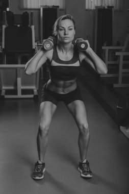 Seksi sarışın kaslı vücudu spor salonunda eğitiyor. Spor sarışın. Güçlü kız.