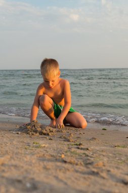 Sahilde erkek şort. Deniz kum ile oynayan çocuk. Sevinç ve eğlenceli çocuklar için. Güzel sıcak bir gün. Çocuk dergi ve Web siteleri için fotoğraf.
