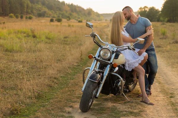 Motociclista e bella ragazza in un campo su una moto . — Foto Stock