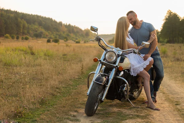 Biker et belle fille dans un champ sur une moto . — Photo