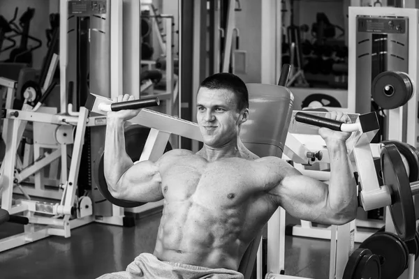 Homme musclé travaillant avec des poids dans la salle de gym. L'homme fait des exercices . — Photo