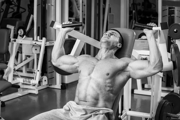 Gespierde man met gewichten in de sportschool uit te werken. Man maakt oefeningen. — Stockfoto