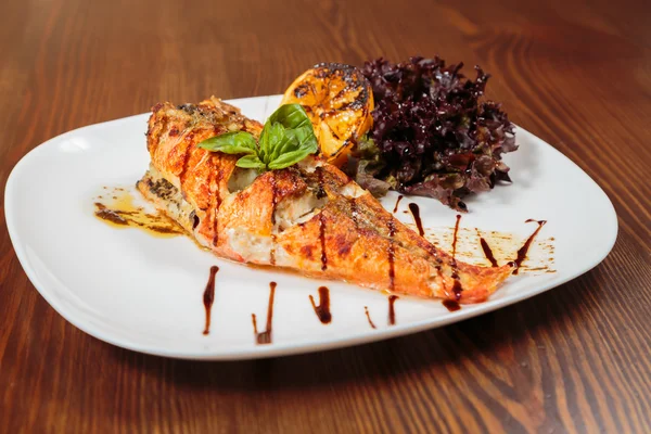 Pescado a la plancha con verduras y salsa a la parrilla. Sabrosa comida mediterránea. Hermosa exposición platos gourmet. La elegancia del gusto y la apariencia de los alimentos. Foto para revistas culinarias . —  Fotos de Stock