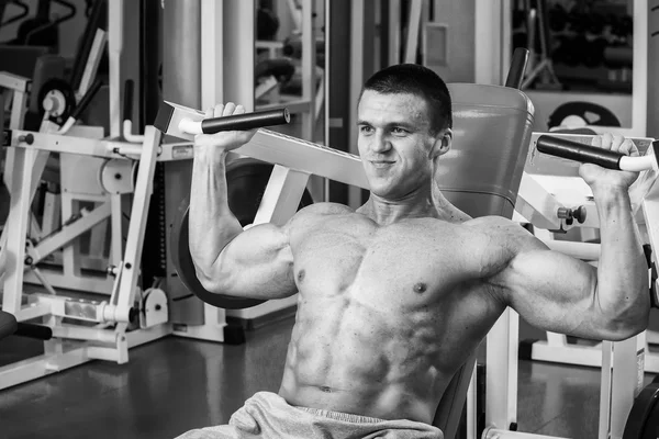 Uomo muscolare che lavora con i pesi in palestra. L'uomo fa esercizi . — Foto Stock
